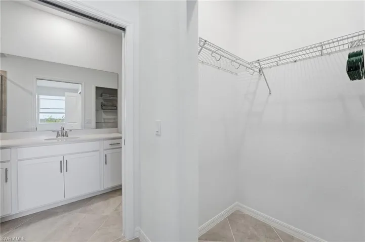 Walk in closet featuring light tile patterned floors and a sink