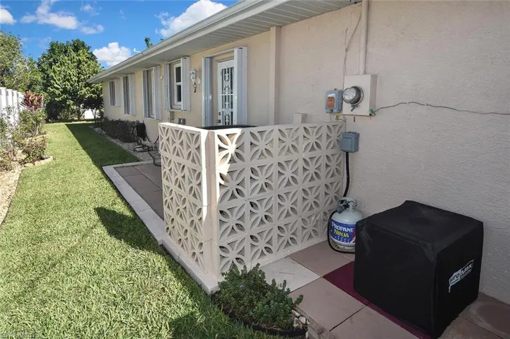 View of side of home featuring a decorative wall shielding the AC condenser with the generator on the other side.