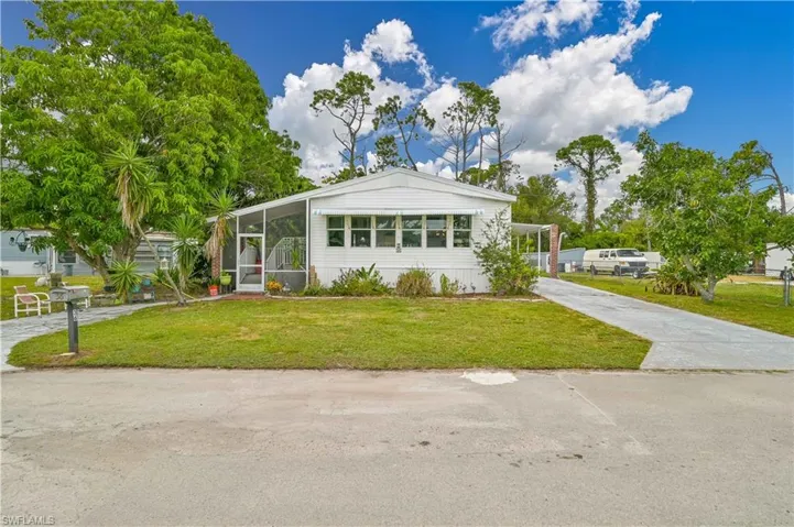 View of front of property with an attached carport, a sunroom, a front lawn, and driveway