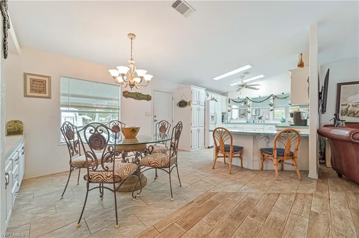 Dining space featuring ceiling fan with notable chandelier, a skylight, and visible vents