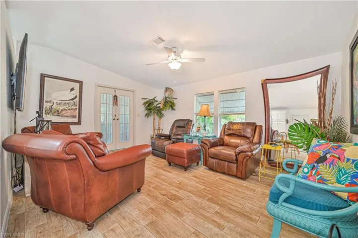 Living area featuring visible vents, ceiling fan, lofted ceiling, and light wood-type flooring