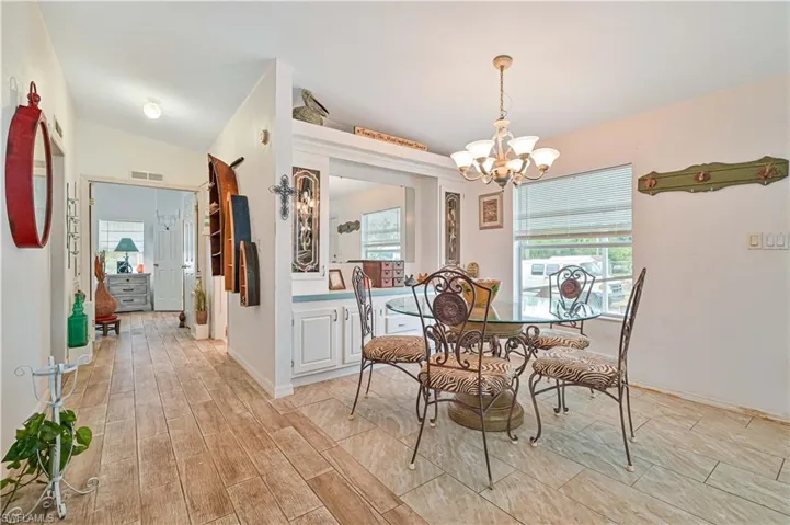 Dining space with lofted ceiling, visible vents, an inviting chandelier, and light wood finished floors