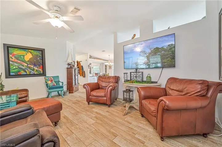Living room with visible vents, light wood-style flooring, and a ceiling fan