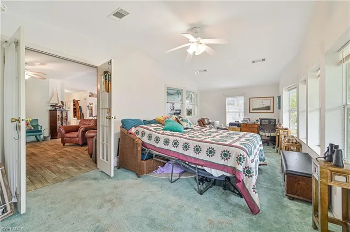 Bedroom featuring lofted ceiling, visible vents, and french doors, Carpet has been removed
