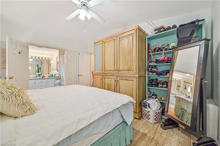 Bedroom featuring ensuite bathroom, a closet, a ceiling fan, lofted ceiling, and light wood-style floors