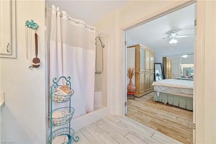 Bathroom featuring ensuite bathroom, a ceiling fan, wood finish floors, and curtained shower