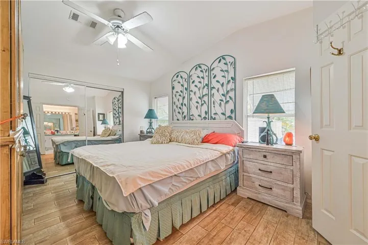 Bedroom with vaulted ceiling, visible vents, light wood-style flooring, and a closet