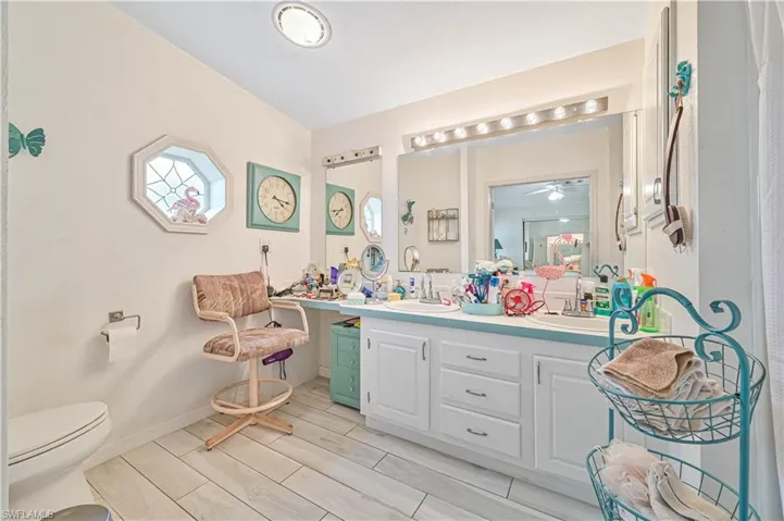 Bathroom with toilet, a sink, wood finish floors, ceiling fan, and double vanity