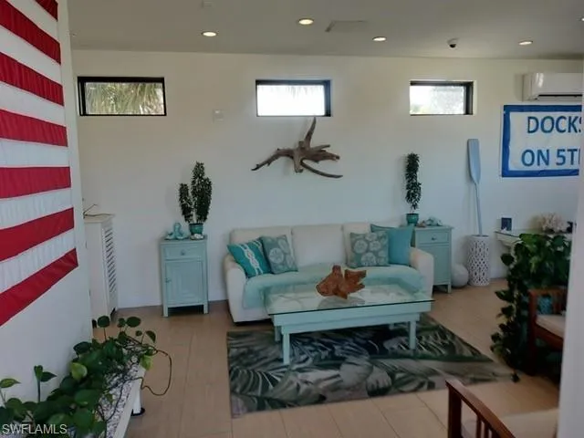 Living room featuring a wall mounted AC and recessed lighting