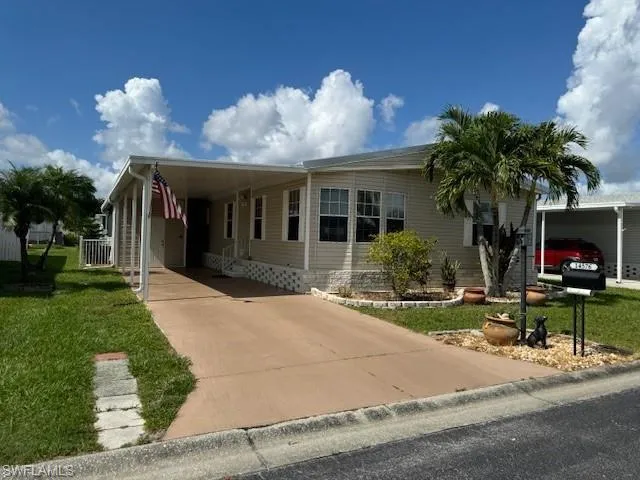Manufactured / mobile home featuring a carport and a front lawn