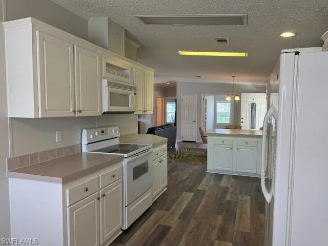 Kitchen featuring dark hardwood / wood-style flooring, a textured ceiling, range, hanging light fixtures, and refrigerator