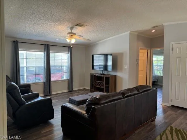 Living room featuring a healthy amount of sunlight, ornamental molding, and dark hardwood / wood-style floors