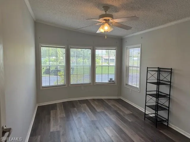 Spare room with crown molding, a textured ceiling, ceiling fan, and dark hardwood / wood-style flooring