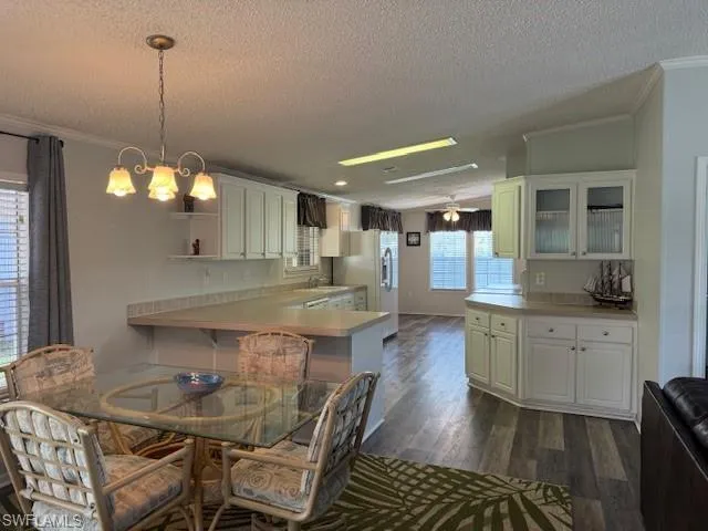 Dining area with dark hardwood / wood-style floors, a textured ceiling, and crown molding