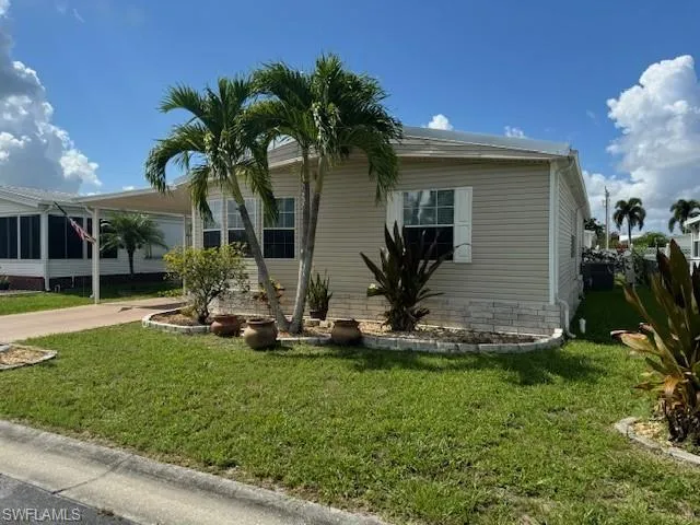 View of property exterior with a lawn and a carport