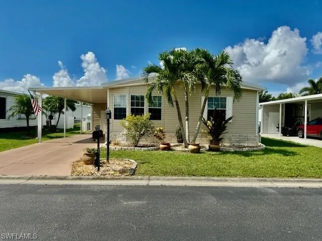 Manufactured / mobile home with a front yard and a carport