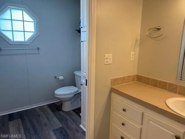 Bathroom featuring wood-type flooring, toilet, and vanity