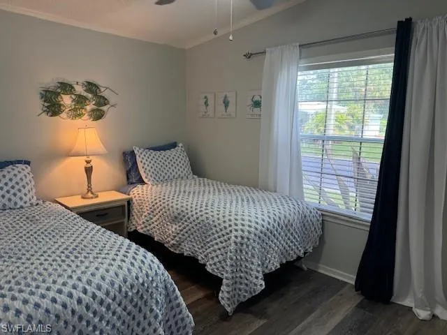Bedroom featuring vaulted ceiling, dark hardwood / wood-style flooring, ornamental molding, and ceiling fan