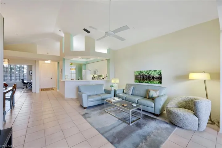 Tiled living room featuring ceiling fan and high vaulted ceiling