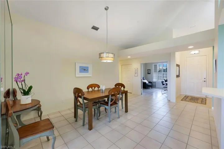 Dining space with light tile patterned floors and vaulted ceiling