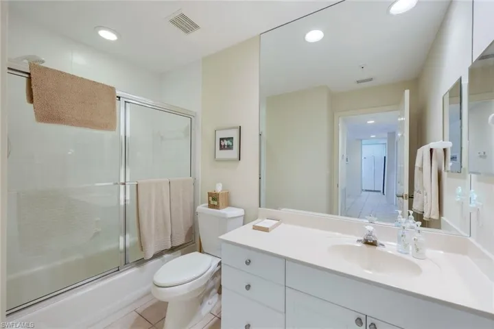 Full Guest bathroom featuring combined bath / shower with glass door, vanity, tile flooring, and toilet