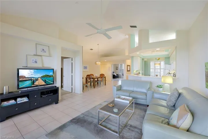 Living room with light tile patterned floors, high vaulted ceiling, and ceiling fan