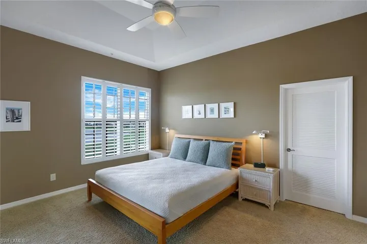 Carpeted bedroom with ceiling fan and Plantation Shutters