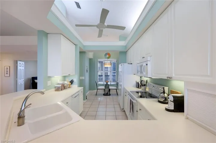 Kitchen with white appliances, ceiling fan, sink, white cabinets, and light tile patterned flooring