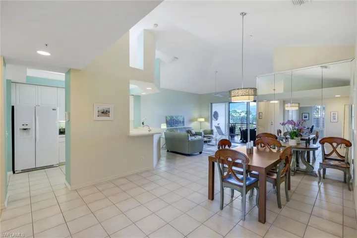 Tiled dining area featuring high vaulted ceiling