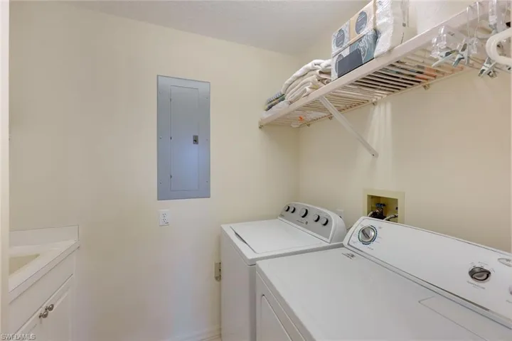 Laundry room featuring cabinets, laundry sink and  independent washer and dryer, a textured ceiling, and electric panel