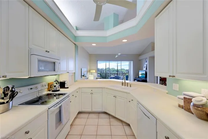 Kitchen featuring white cabinetry, sink, lofted ceiling, white appliances, and light tile patterned floors