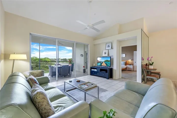 Living room with ceiling fan, light tile patterned floors, and high vaulted ceiling