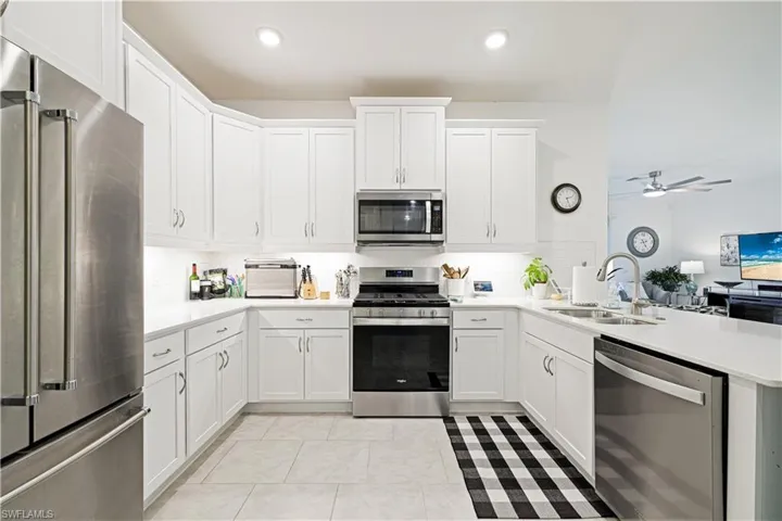 Kitchen featuring stainless steel appliances, a peninsula, light countertops, ceiling fan, and white cabinetry