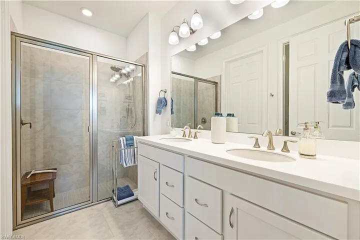 Bathroom with double vanity, a stall shower, and tile patterned flooring