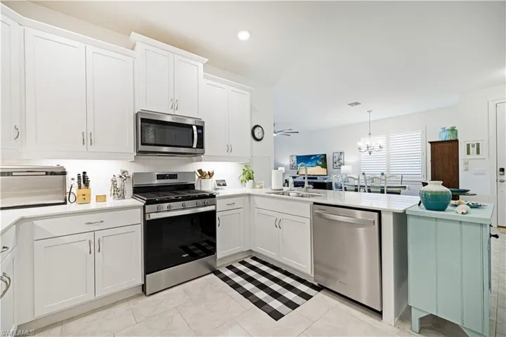 Kitchen featuring appliances with stainless steel finishes, tasteful backsplash, a peninsula, light countertops, and recessed lighting