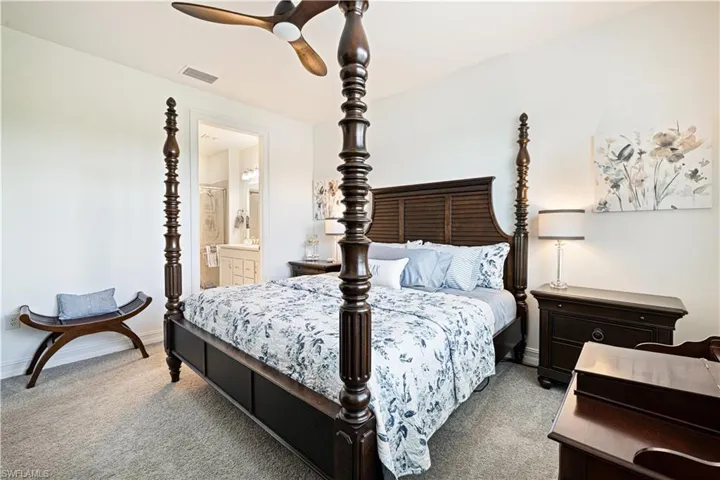 Carpeted bedroom with ensuite bathroom and a ceiling fan