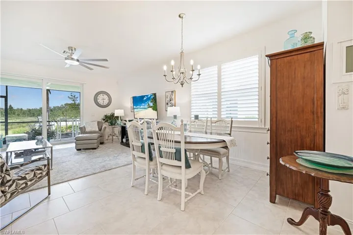 Dining space with healthy amount of natural light, light tile patterned floors, and a chandelier