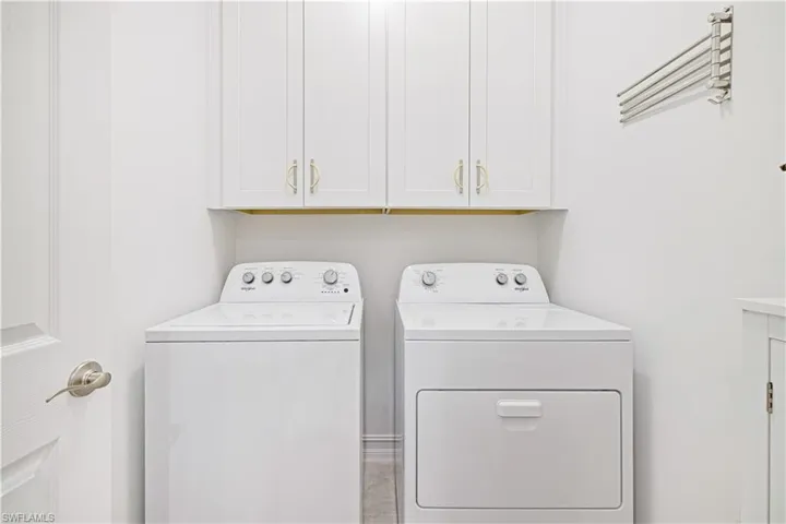 Washroom with washer and clothes dryer and cabinet space
