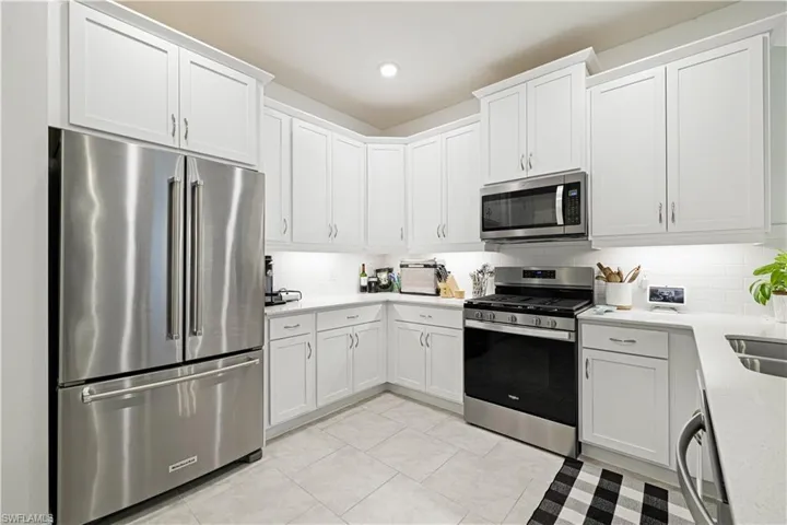 Kitchen featuring stainless steel appliances, light countertops, tasteful backsplash, white cabinetry, and recessed lighting