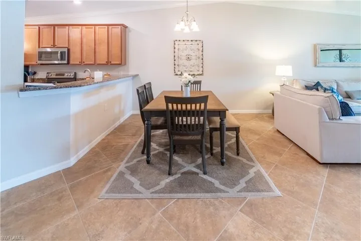 Tiled dining area with lofted ceiling, crown molding, an inviting chandelier, and sink
