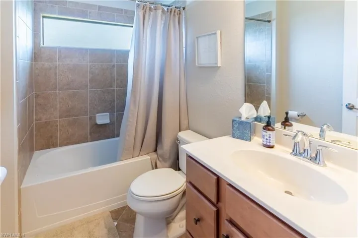 Full bathroom with vanity, toilet, shower / bathtub combination with curtain, and tile patterned flooring