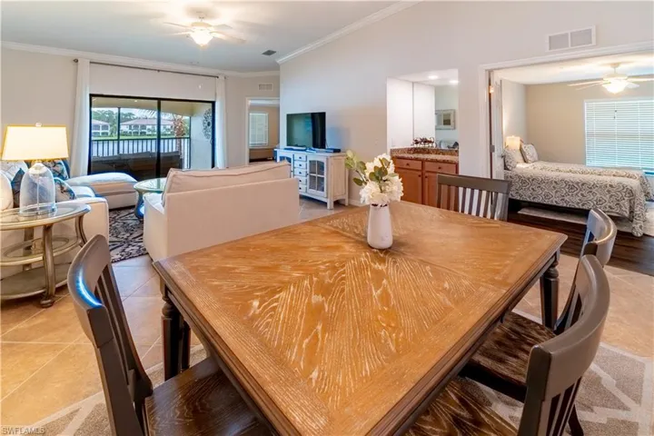 Tiled dining space with ornamental molding, vaulted ceiling, and ceiling fan
