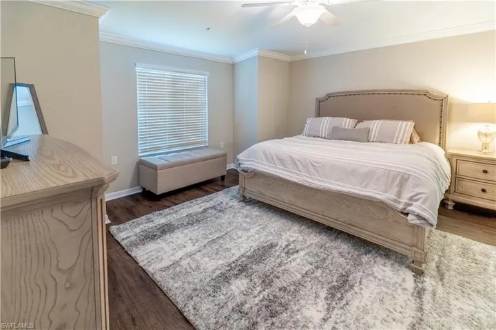Bedroom with crown molding, ceiling fan, and dark hardwood / wood-style flooring