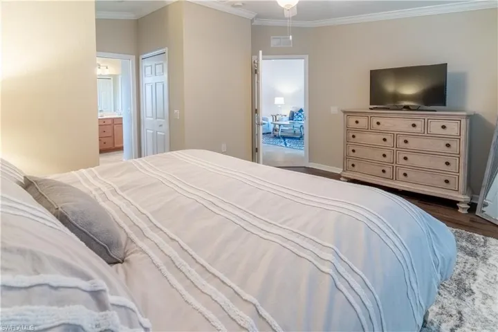 Bedroom with crown molding, wood-type flooring, a closet, and ensuite bath