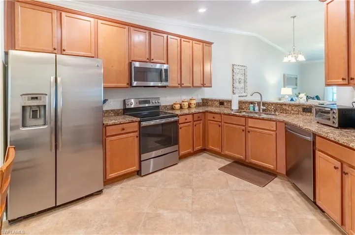 Kitchen featuring hanging light fixtures, stainless steel appliances, sink, vaulted ceiling, and an inviting chandelier