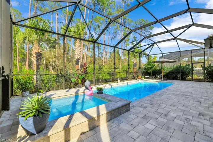 View of pool with screen enclosure and under-roof patio area