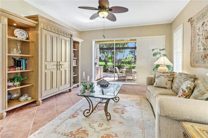 Living room featuring ornamental molding, light tile patterned flooring, and ceiling fan