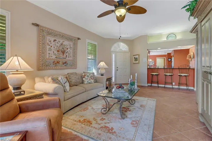 Living room with light tile patterned flooring, ornamental molding, and ceiling fan