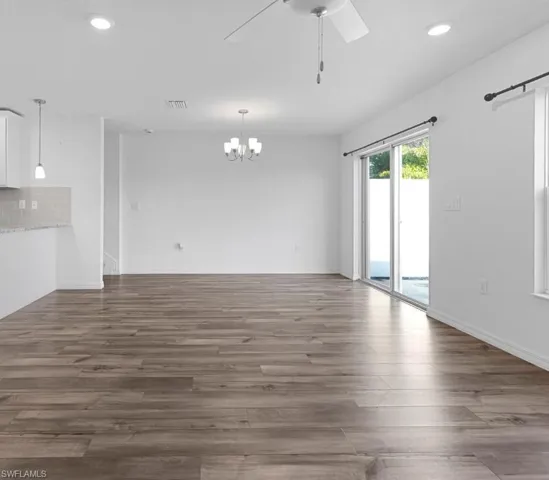 Unfurnished dining area with a ceiling fan, suspended lighting, and dark wood-style flooring