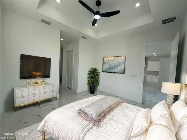 Bedroom featuring marble finish floor, a tray ceiling, visible vents, and baseboards